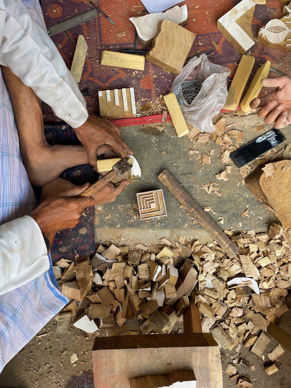 a busy scene of a artisan from jaipur meticulously working on a piece of wood.