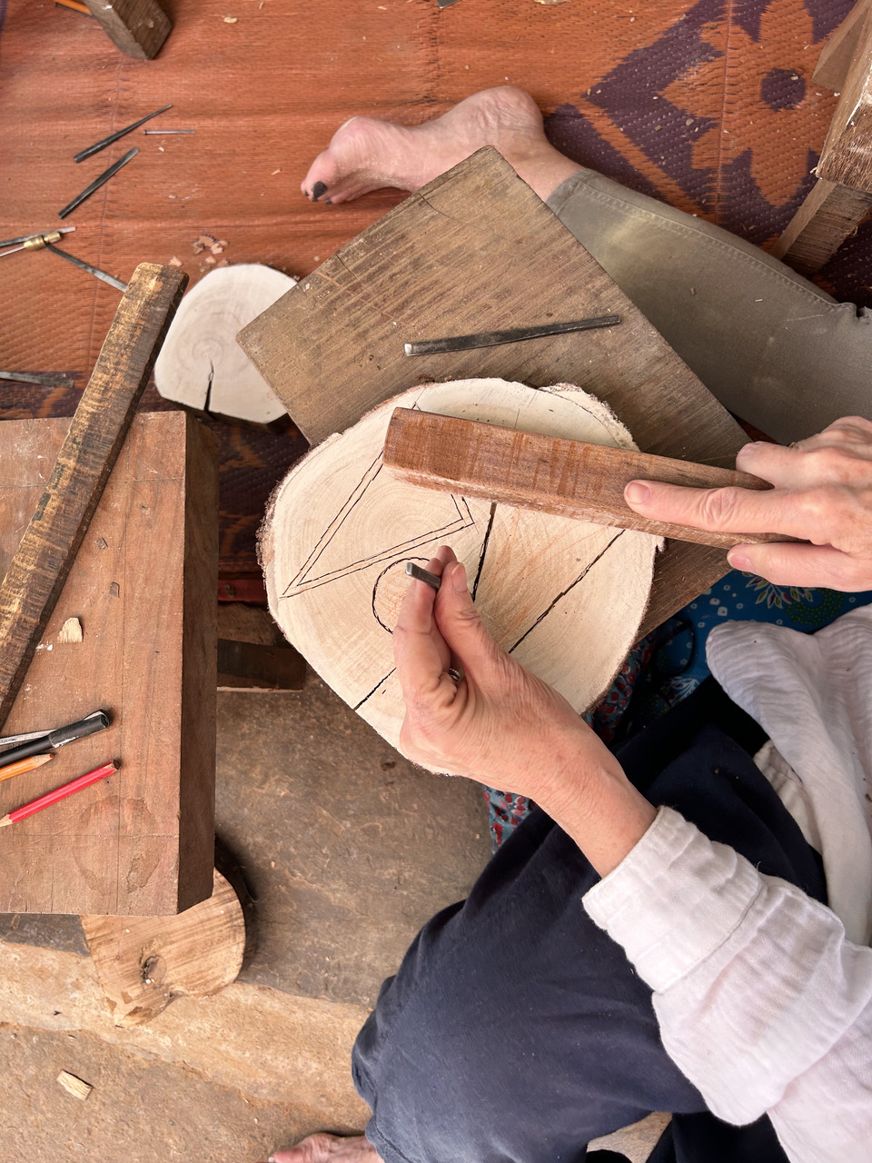 the person is using a metal tool to create or modify the piece of wood, a form of craftsmanship.