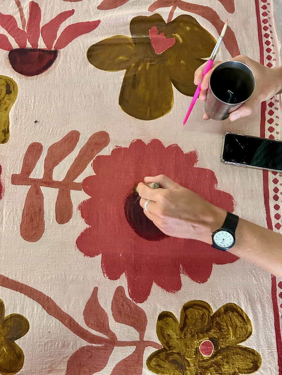 Close-up of a young girl applying block printing pastes with brush during the hands-on workshop session.