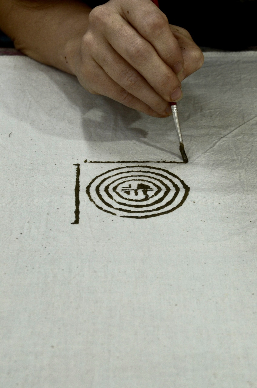 An attendee creating a pattern on the cloth using a paint brush