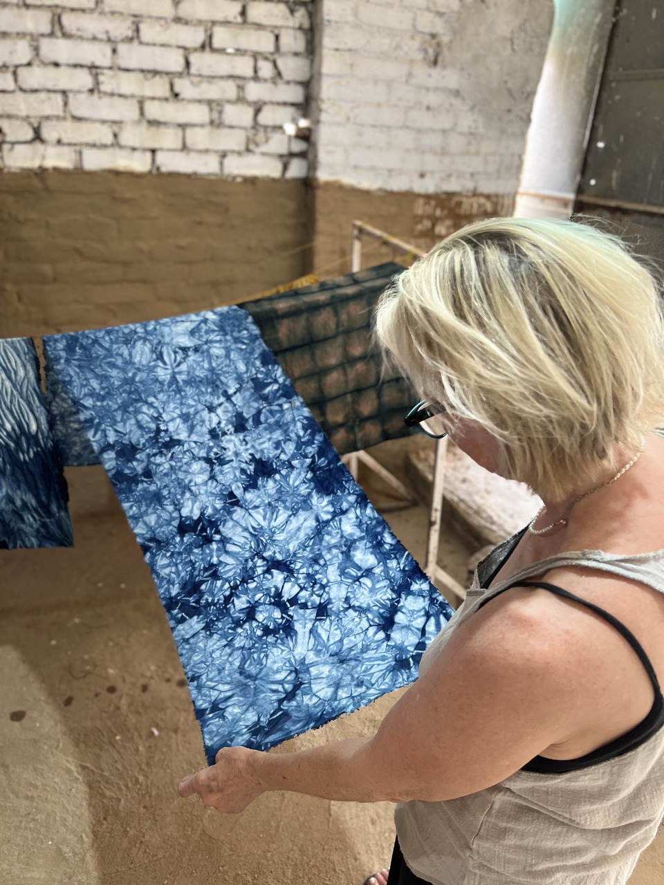 A woman carefully observing the indigo tie and die small fabric swatch created by her.