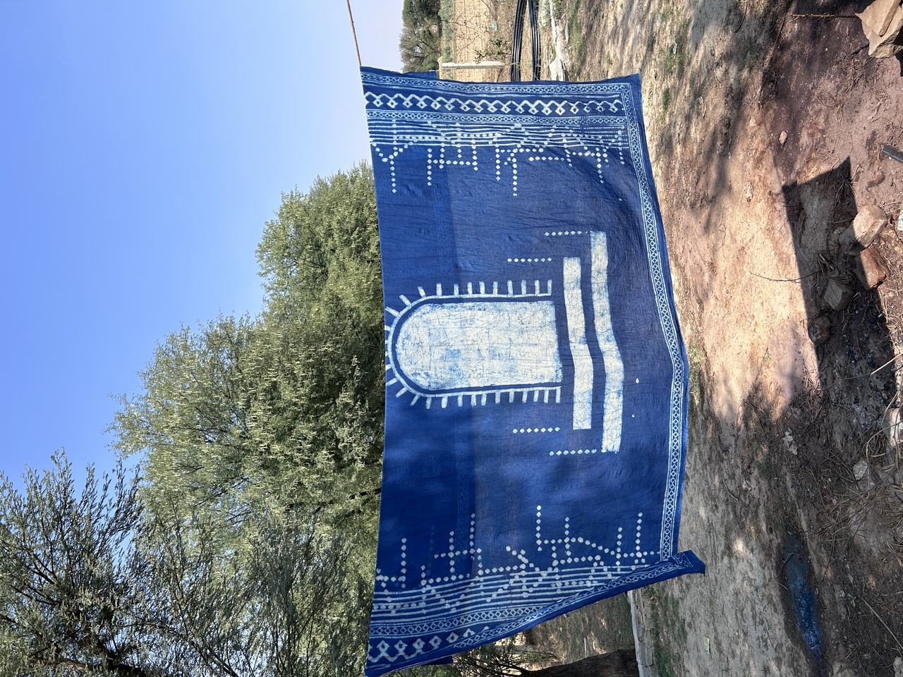 A piece of blue block printed fabric dying in the the outdoors.