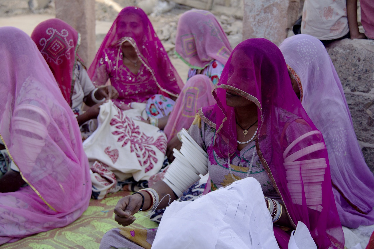 A couple of rural women from the village sitting altogether to perform the activity of hand sewing